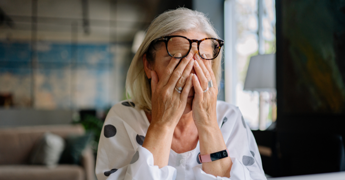 Person covering their eyes, appearing stressed, representing Stress Awareness Month.