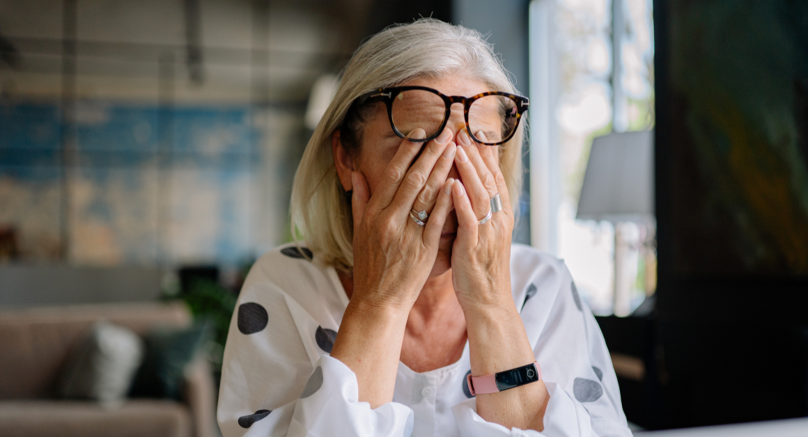 Person covering their eyes, appearing stressed, representing Stress Awareness Month.