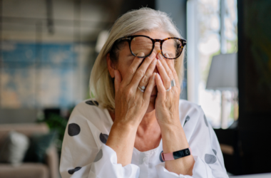 Person covering their eyes, appearing stressed, representing Stress Awareness Month.