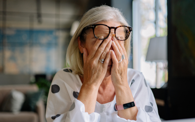 Person covering their eyes, appearing stressed, representing Stress Awareness Month.