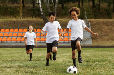 Three young boys are actively playing soccer on a grassy field, showcasing teamwork and enthusiasm.