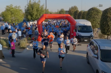 Participants run through the starting arch at the beginning of a community 5K race.