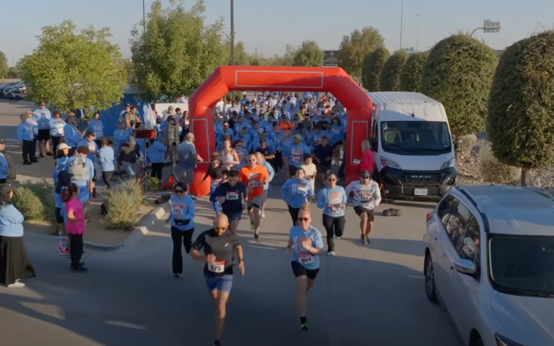 Participants run through the starting arch at the beginning of a community 5K race.