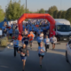 Participants run through the starting arch at the beginning of a community 5K race.