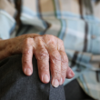 Close-up of an older adult’s hand resting on their knee, representing arthritis and joint health.