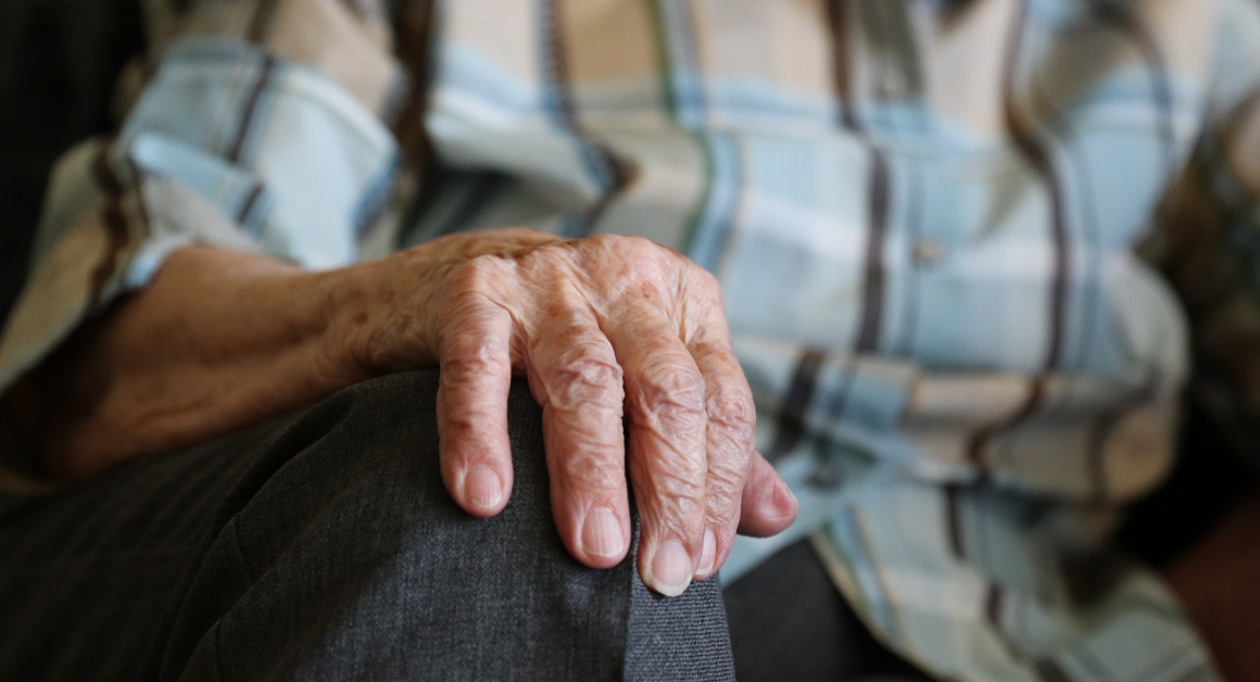 Close-up of an older adult’s hand resting on their knee, representing arthritis and joint health.