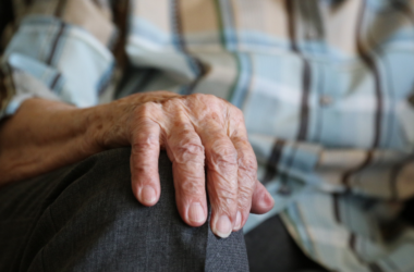 Close-up of an older adult’s hand resting on their knee, representing arthritis and joint health.