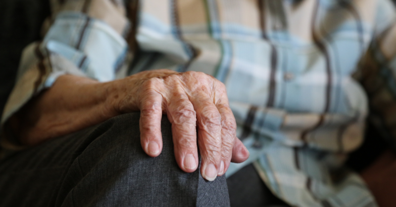 Close-up of an older adult’s hand resting on their knee, representing arthritis and joint health.