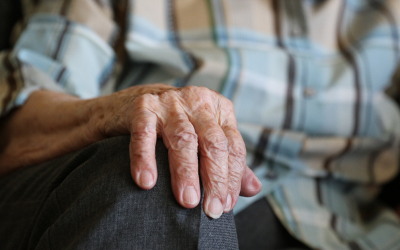 Close-up of an older adult’s hand resting on their knee, representing arthritis and joint health.