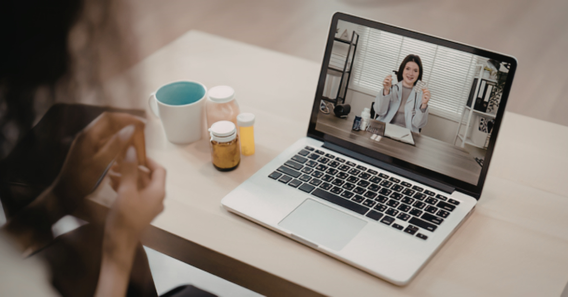 A sick patient having a telehealth call with a health professional over a computer.