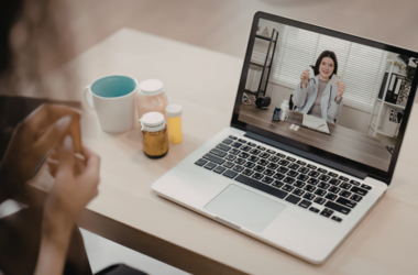 A sick patient having a telehealth call with a health professional over a computer.