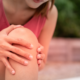 Close up of a person holding their knee with pain, representing ommon spring injuries.