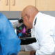 Dr. Jesus Gomez, a board-certified medical hematologist and oncologist examines colorful data via a microscope on a computer screen.