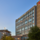 Modern hospital building with glass windows at dusk, labeled "El Paso Children's." Nearby, a tree and parking structure under a clear sky.