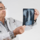 A doctor looking closely at some x-rays, referencing lung health.