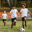 Three young boys are actively playing soccer on a grassy field, showcasing teamwork and enthusiasm.