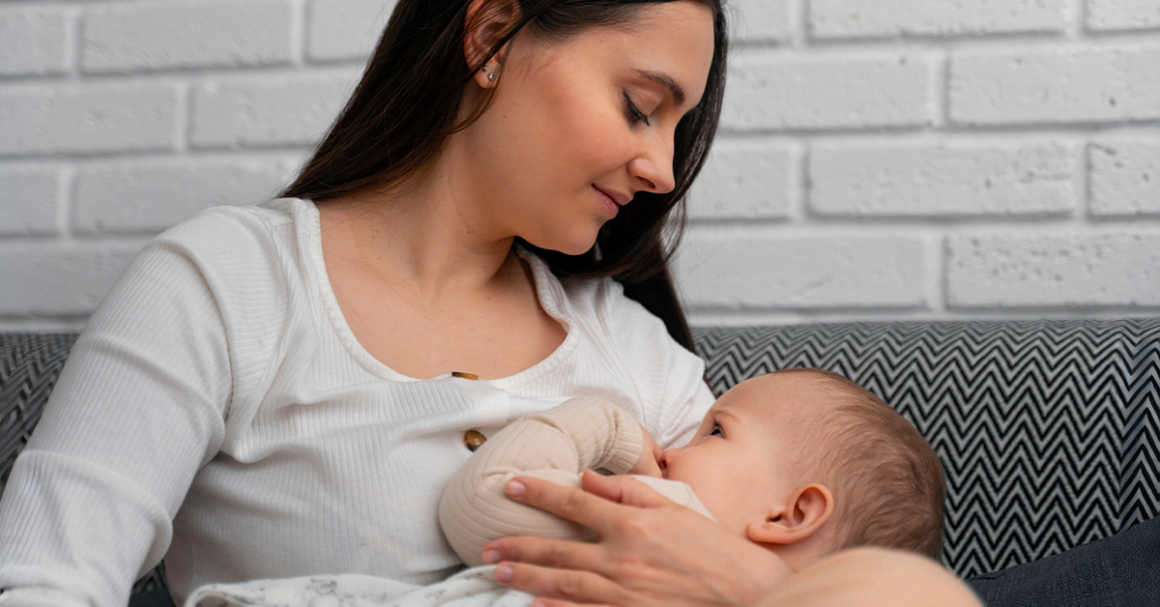 A woman breastfeeding an infant while sitting on a couch at home.