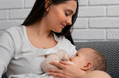 A woman breastfeeding an infant while sitting on a couch at home.