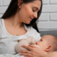 A woman breastfeeding an infant while sitting on a couch at home.