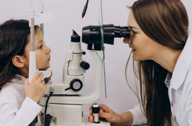Eye doctor examines a young child's eyes using a slit lamp during an eye exam.