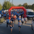 Participants run through the starting arch at the beginning of a community 5K race.