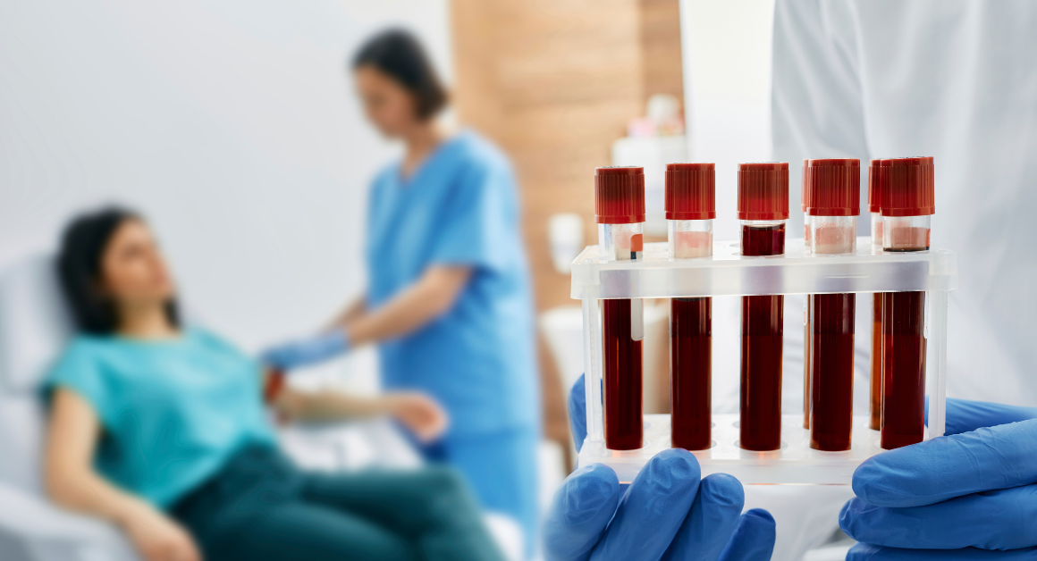 A healthcare professional holding a tray of blood samples in the foreground. In the background, a nurse prepares a patient for a blood draw, creating a clinical and focused atmosphere.