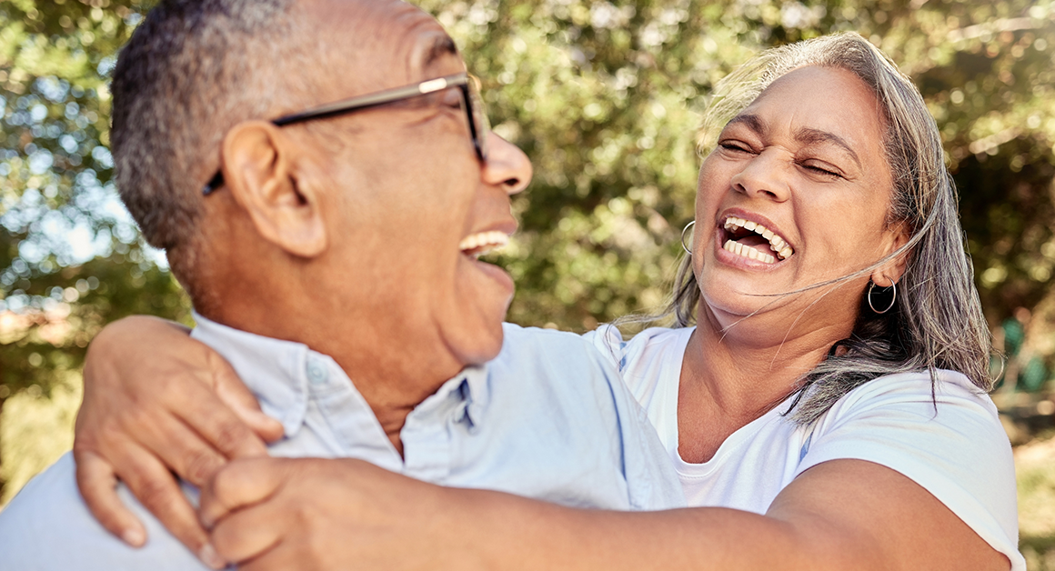 Older couple laughing together outdoors, reflecting connection, well-being, and healthy aging.