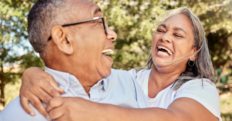 Older couple laughing together outdoors, reflecting connection, well-being, and healthy aging.