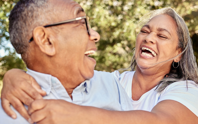 Older couple laughing together outdoors, reflecting connection, well-being, and healthy aging.