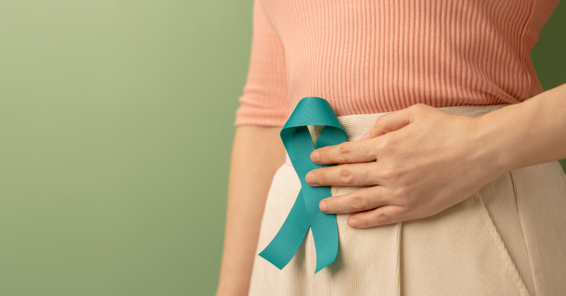 Person holding a teal awareness ribbon against their abdomen, representing ovarian cancer awareness and support.