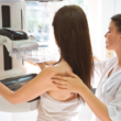 A healthcare professional assists a patient during a mammogram screening.