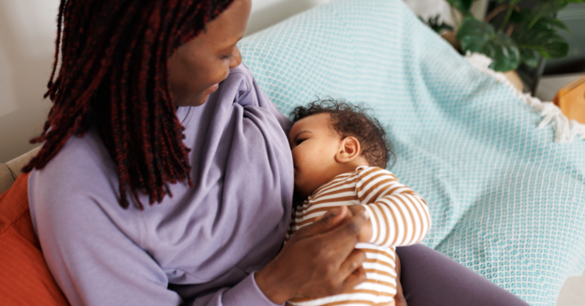 A mother breastfeeds her baby while holding the infant comfortably in her arms.