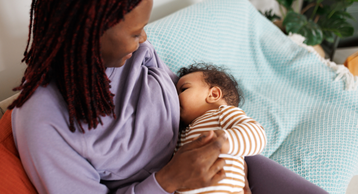 A mother breastfeeds her baby while holding the infant comfortably in her arms.