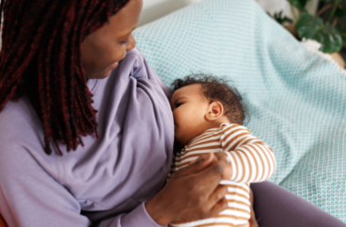 A mother breastfeeds her baby while holding the infant comfortably in her arms.