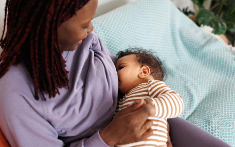 A mother breastfeeds her baby while holding the infant comfortably in her arms.