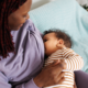 A mother breastfeeds her baby while holding the infant comfortably in her arms.
